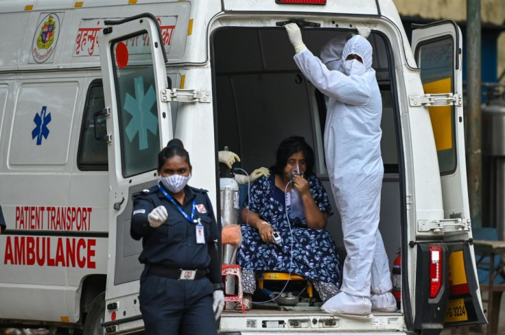 A health worker wearing Personal Protective Equipment gear stands with a patient getting transferred to an intensive care unit in Mumbai