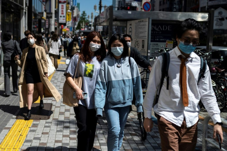 Pedestrians walk in Tokyo's Shinjuku area ahead of a declaration of a new coronavirus state of emergency expected Friday