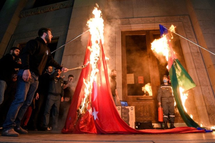 Men set fire to a Turkish national flag (L) and an Azerbaijan national flag in Yerevan, late on April 23, 2021, as Armenians mark the 106th anniversary of World War I-era mass killings. Armenians mark the 106th anniversary of the massacres in which they s