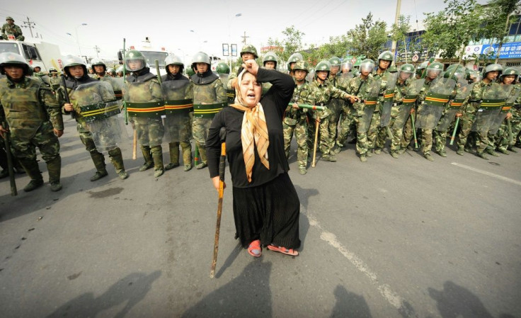 This file photo taken on July 7, 2009 shows Chinese riot police watching a Muslim ethnic Uyghur woman protesting in Urumqi, the capital of China's Xinjiang region