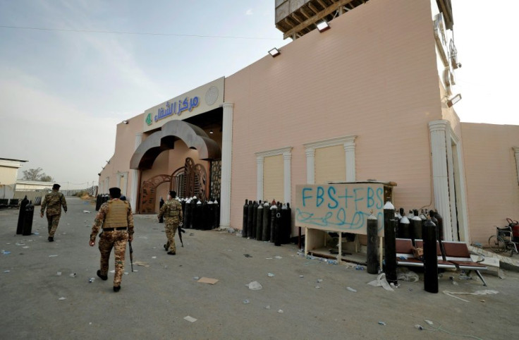 Iraqi security forces stand at the gate of Ibn Al-Khatib Hospital in Baghdad, on April 25, 2021, after a deadly fire killed scores, including severely ill Covid patients and relatives