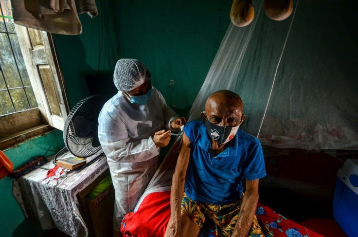 A man is vaccinated against Covid-19 by a health worker in a remote area of Moju, Para state, Brazil