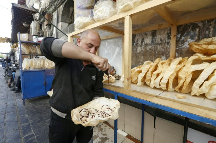 A Syrian vendor spreads grape molasses on a traditional sweet known as "naeem", a traditional treat served during Ramadan