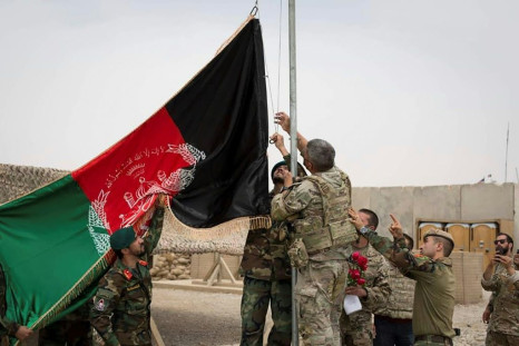 US troops and Afghan National Army (ANA) soldiers raise Afghanistan's national flag during a handover ceremony at Camp Antonik in Helmand province