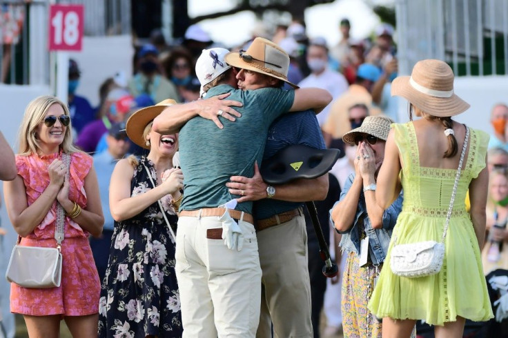 Sam Burns, his back to the camera, hugs his father as he celebrates with his family on the 18th green after winning his first US PGA title at the Valspar Championship