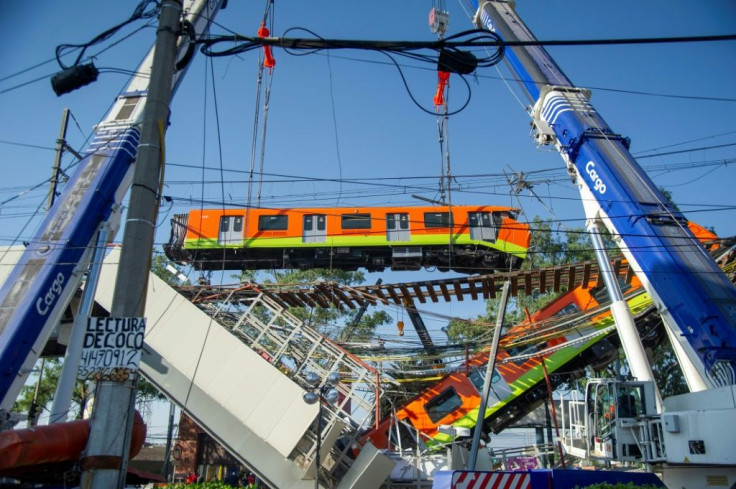 Rescue workers use cranes to remove the wreckage of a metro train that fell as an overpass collapsed in Mexico City