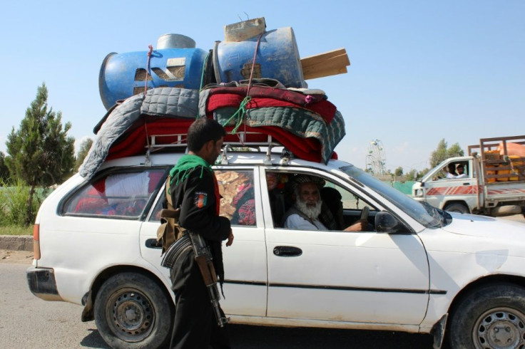 A policeman stands guard at a road checkpoint as an internally displaced family flees from the ongoing fighting between Afghan security forces and Taliban fighters, on the outskirts of Lashkar Gah on May 5, 2021