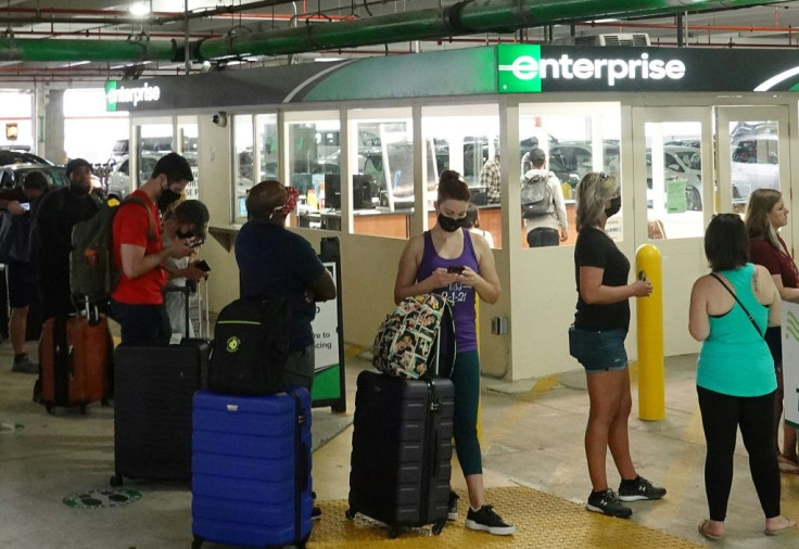 People wait in line at an Enterprise rental agency at Miami International Airport in April 2021
