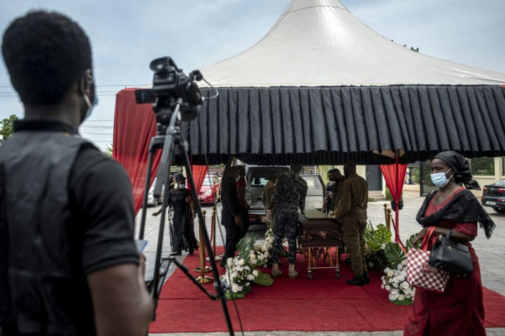 A cameraman films pallbearers carrying a coffin during a funeral ceremony in Accra