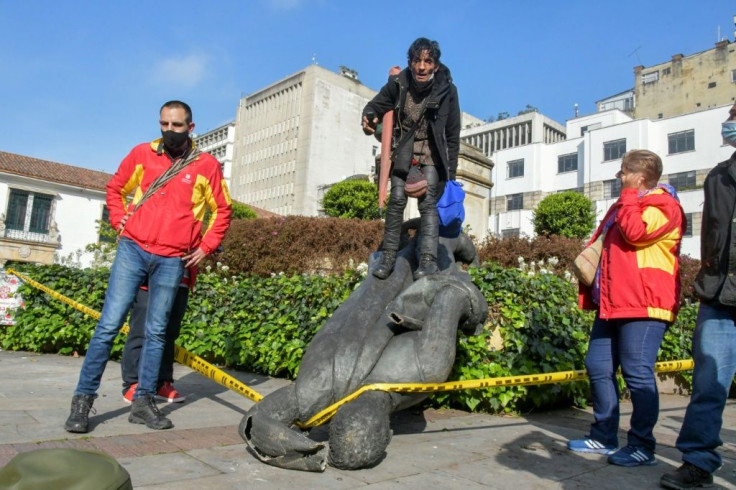 A Misak indigenous man stands atop the statue of Spanish conquistador Gonzalo Jimenez de Quesada after knocked it down in Bogota on May 7, 2021