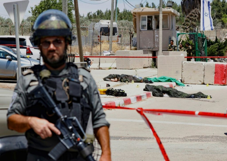 An Israeli soldier stands in front of the bodies of two Palestinians shot dead after they were reported to have opened fire on an Israeli base