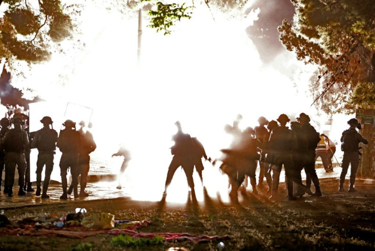 Israeli security forces form a shield as a stun grenade bursts amid clashes with Palestinian protesters at the al-Aqsa mosque compound in Jerusalem