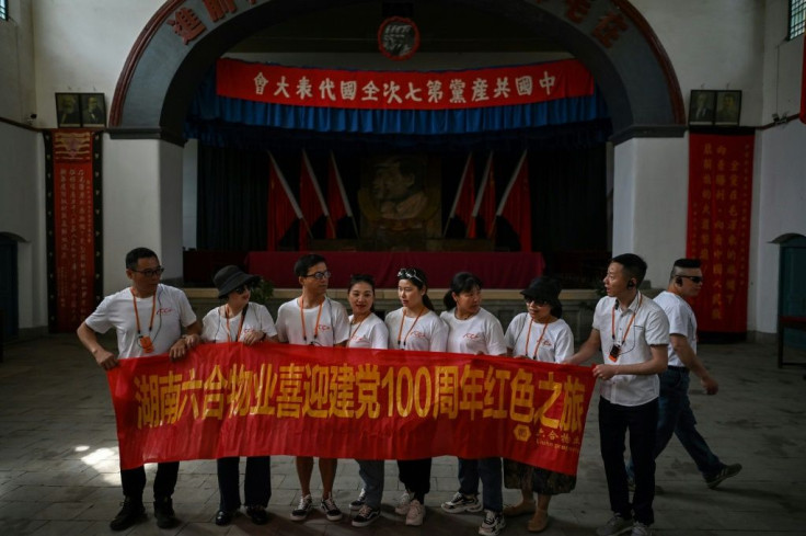 This picture taken during a government-organised media tour shows tourists wearing commemorative T-shirts and unfurling a banner in Yan'an