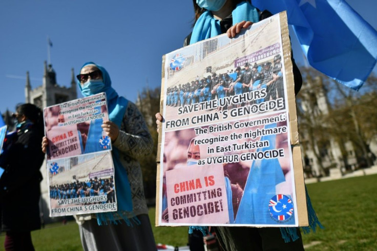 Members of the Uyghur community hold placards as they demonstrate to call on the British parliament to vote to recognise alleged persecution of China's Muslim minority Uyghur people as genocide and crimes against humanity in London on April 22, 2021