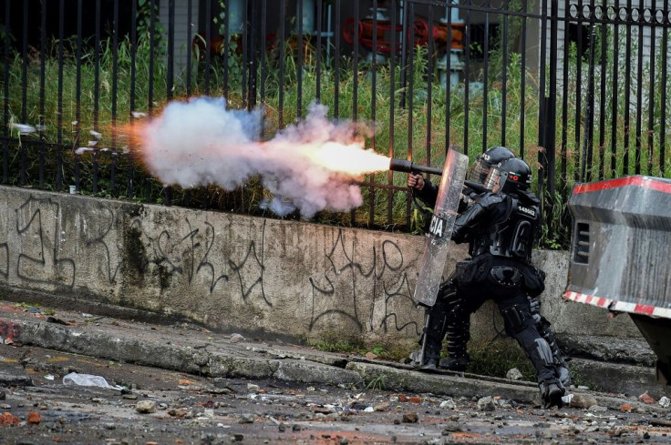 A riot police officer fires tear gas at demonstrators in Colombia, where anti-government protests have turned deadly