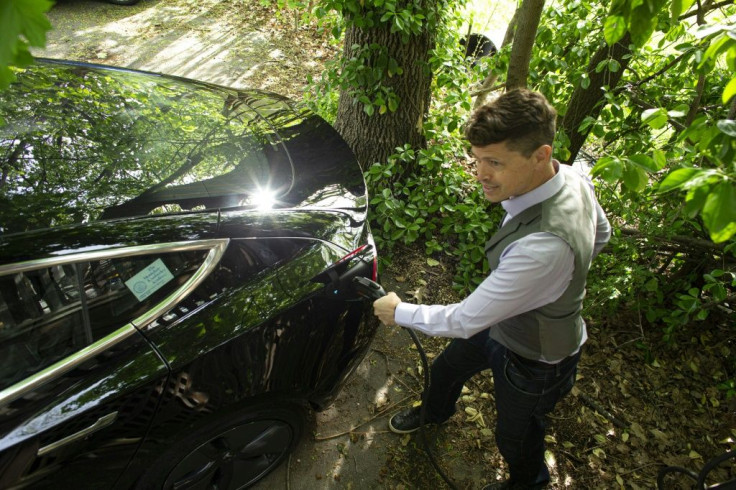 Ben Rich charges his Tesla vehicle in his backyard in Montclair, New Jersey on May 06, 2021. With more electrical models soon hitting showrooms, the focus will shift to consumer willingness to pivot to electric cars at a time when conventional gas station