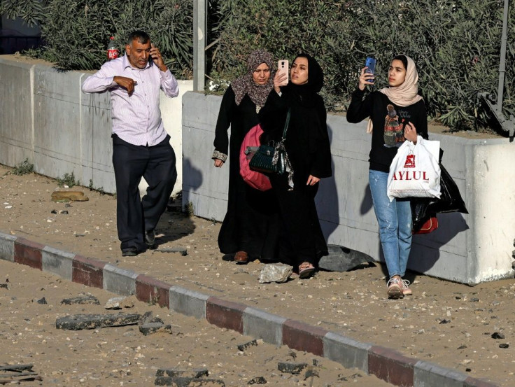 Palestinian women take photos of damaged buildings following Israeli airstrikes on Gaza City early on May 12