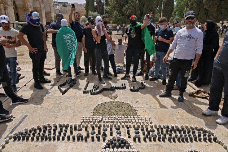 Palestinians gather around an installation made with empty shells of stun grenades and tear gas canisters depicting the Dome of the Rock with the Arabic slogan "you shall not pass", at Jerusalem's Al-Aqsa mosque complex on May 10