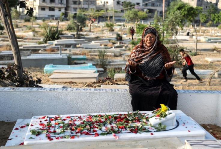 A Palestinian Muslim woman prays at the grave of a relative in Beit Lahia in the Gaza Strip on the first day of Eid al-Fitr, as the worst flare-up of Israeli-Palestinian violence in seven years clouds the three-day holiday