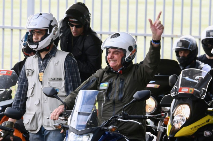 Brazil's President Jair Bolsonaro waves to supporters as he rides a motorcycle leading a caravan of more than 1000 bikers May 9, 2021