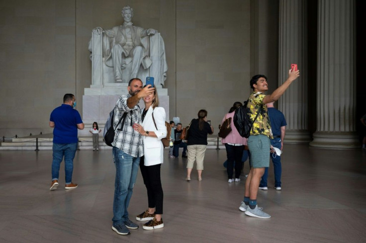 Tourists, some wearing face masks and others unmasked, visit the Lincoln Memorial