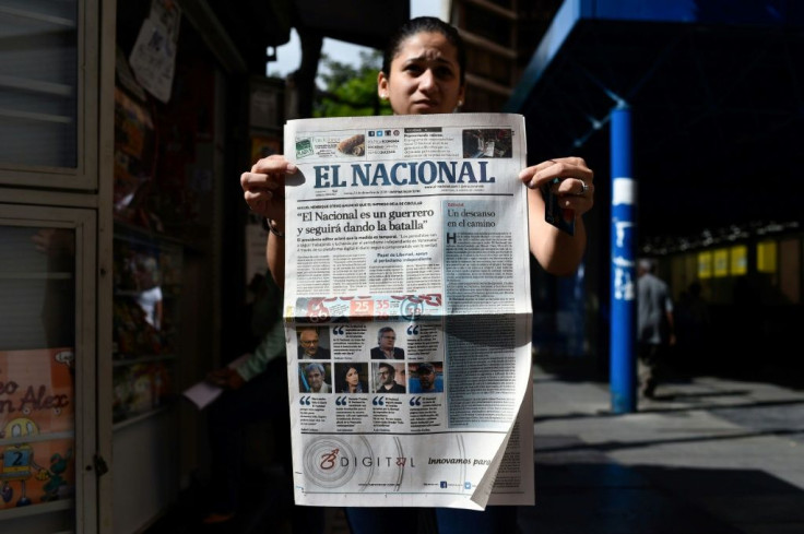 A woman holds up the final printed edition of El Nacional on December 14, 2018, with its front page reading "El Nacional is a warrior and will keep on fighting"