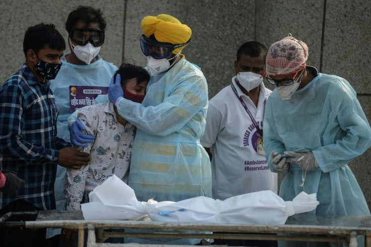 At the New Delhi crematorium, a volunteer comforts a relative of a child who died of Covid-19