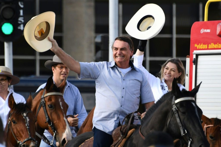 Brazilian President Jair Bolsonaro (C) arrives on horseback at a demonstration by farmers in Brasilia, on May 15, 2021