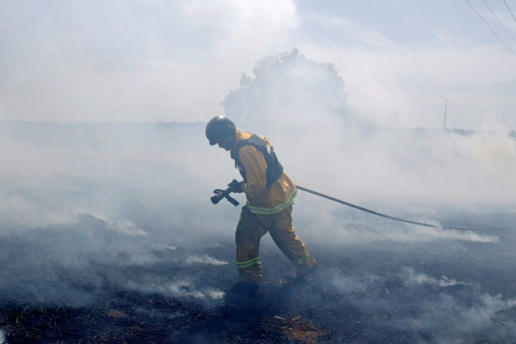 An Israeli firefighter extinguishes a fire caused by rockets launched from the Gaza Strip