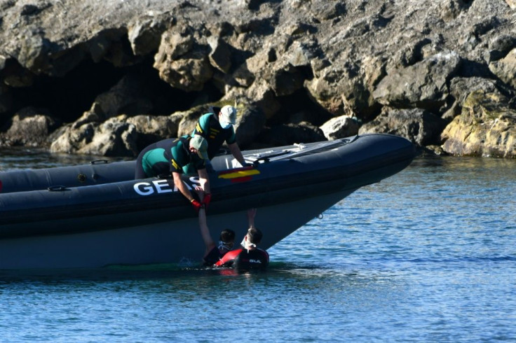 Spanish Civil guards pull a migrant into an inflatable boat after he arrived swimming to the Spanish enclave of Ceuta from neighbouring Morocco on May 17, 2021