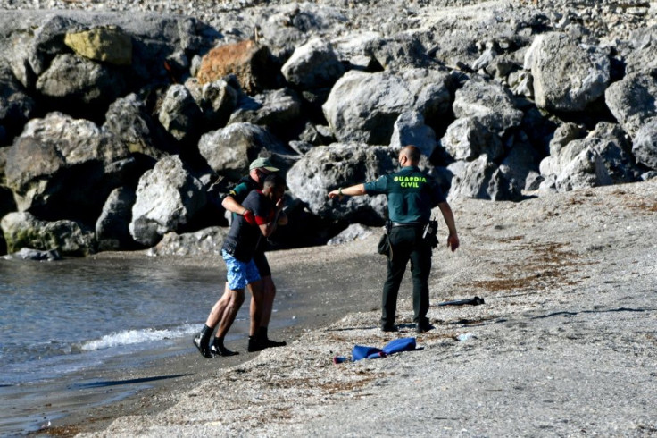 Spanish Civil guards help a migrant after he arrived swimming to the Spanish enclave of Ceuta from neighbouring Morocco on May 17, 2021