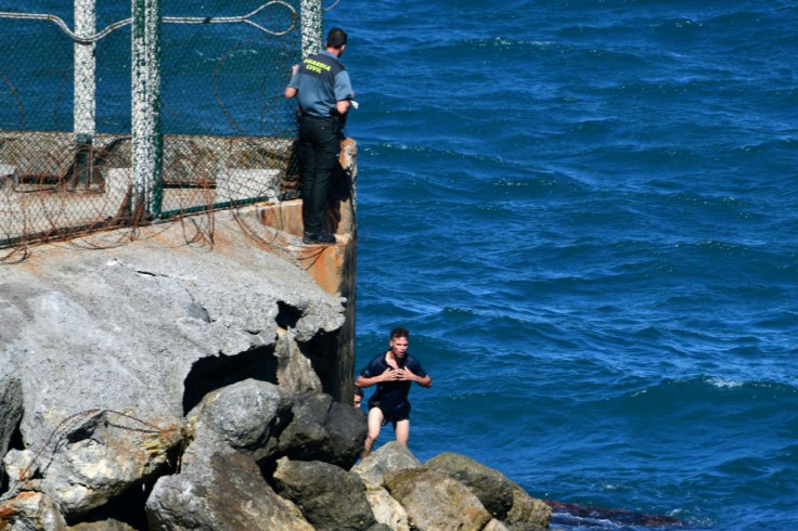 Migrants try to enter either by scaling the tall barrier fence or swimming