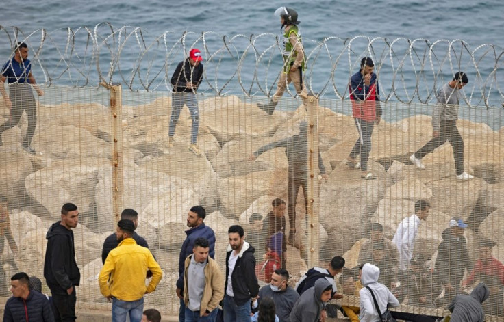 Migrants slip through a fence in the northern town of Fnideq in an attempt to cross the border from Morocco to Spain's North African enclave of Ceuta