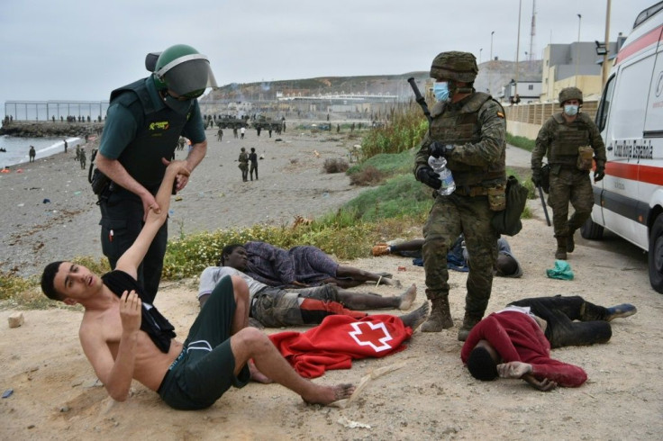 A Spanish Civil Guard officer holds a migrant who arrived swimming at the Spanish enclave of Ceuta