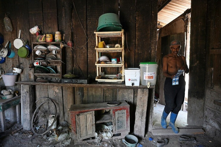 Orlando Chavez walks through his kitchen after performing back-breaking work collecting African palm bunches, in El Progreso, Honduras