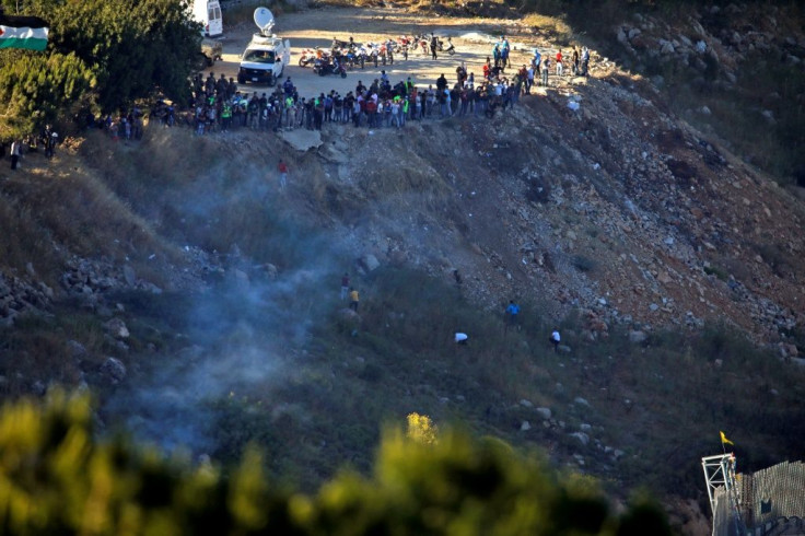 Pro-Palestinian Lebanese protesters run for cover after erecting a Hezbollah flag on the border fence with Israel on May 18, 2021