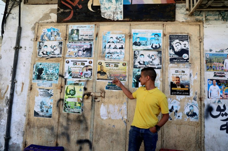 Palestinian Ashraf Ahmed stands in front of a wall lined with posters of "martyrs" of the two Palestinian uprisings (intifadas)