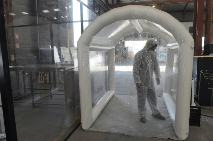 Employees at French company Tri-o et Greenwishes are sprayed down with disinfectant after working with potentially contaminated masks