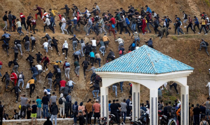 Migrants scramble from the Moroccan police as they try to reach the border between Morocco and thr Spanish enclave of Ceuta on May 18