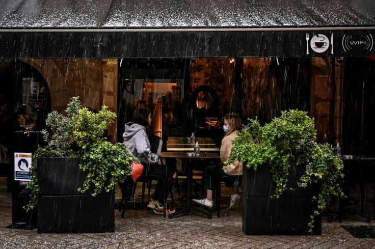Customers sit under an awning on a cafe terrace in Lyon, south-eastern France on May 19, 2021, during a downpour, as cafes, restaurants and other businesses re-opened after closures during the coronavirus (Covid-19) pandemic.