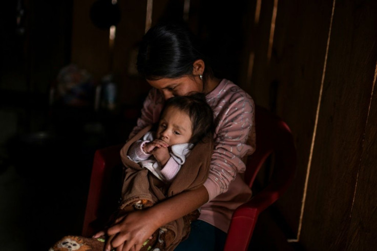 A Mexican mother holds her baby at her home in Metlatonoc in Guerrero state, where calls are growing for an end to the ancestral tradition of selling daughters into marriage