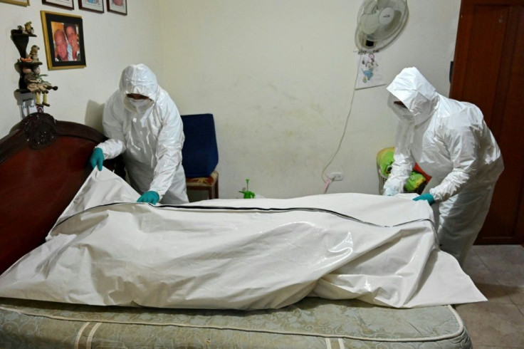 Funeral home workers prepare to carry the corpse of a man who died allegedly from COVID-19 from his home in Cali, Colombia, in July 2020