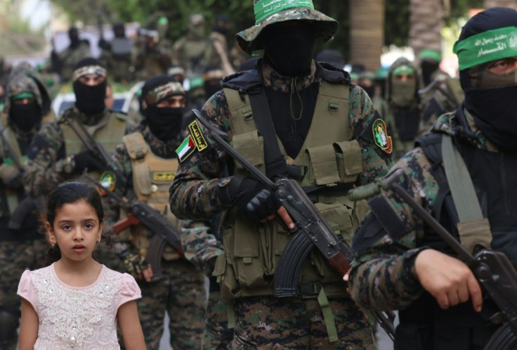 A girl looks on as members of Al-Qassam brigades, the armed wing of the Palestinian Hamas group, march in Gaza City on May 22 in commemoration of senior Hamas commander Bassem Issa who was killed in am Israeli airstrike
