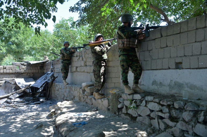Members of Afghan security forces take positions during clashes with Taliban forces in Mihtarlam
