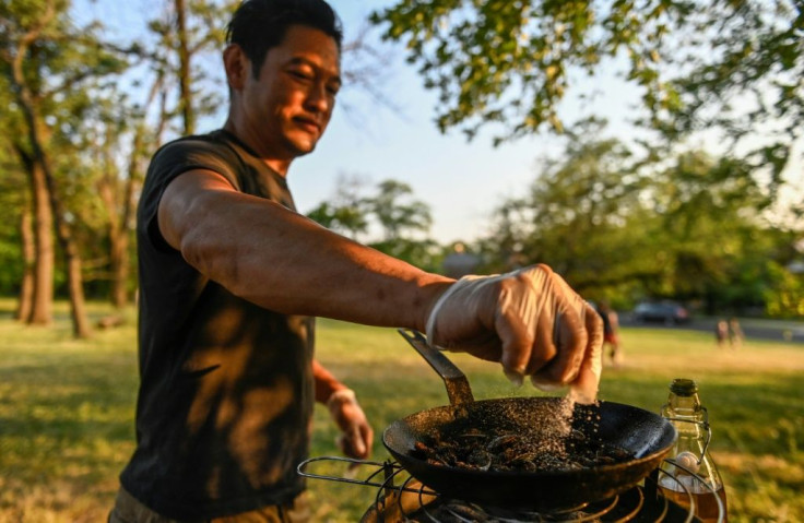 Chef Bun Lai seasons cicadas with salt as he fries them at Fort Totten Park in Washington