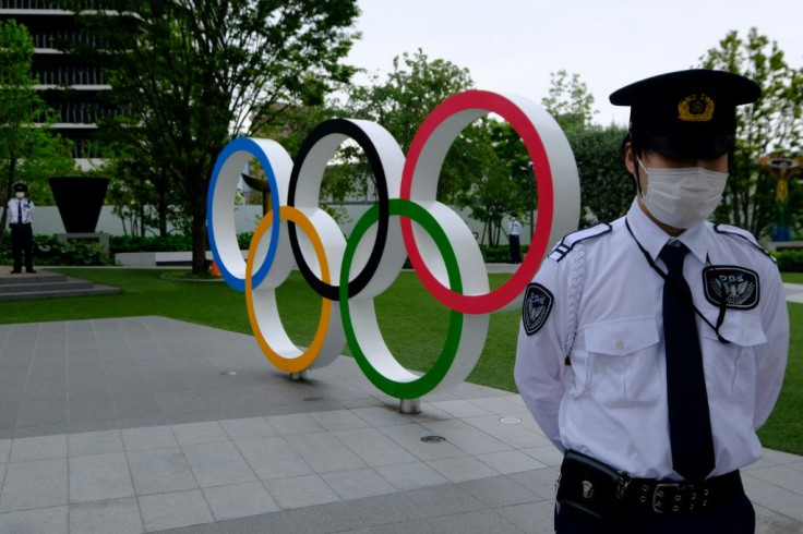 Security guards keep watch next to the Olympic Rings while people take part in a protest against the hosting of the 2020 Tokyo Olympic Games, in front of the headquarters building of the Japanese Olympic Committee in Tokyo, on May 18 2021