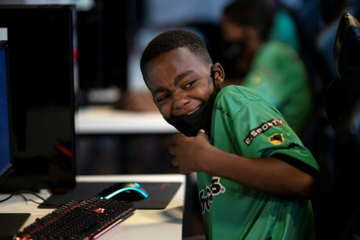 A boy smiles while playing a video game called League of Legends (LoL) at the NGO AfroReggae headquarters