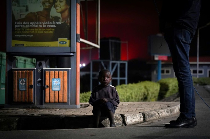 A lost child sits on a curb as people flee from Goma. UNICEF has said dozens of children have been separated from their parents