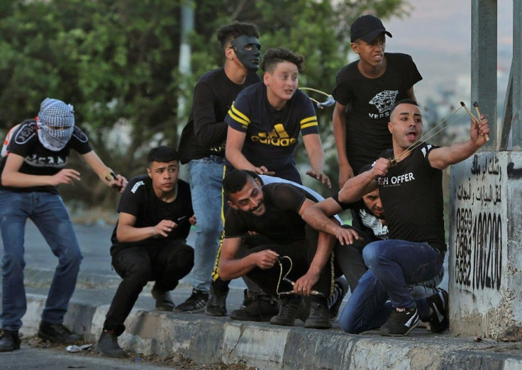 Palestinian protesters use slingshots during clashes with Israeli security forces at the Hawara checkpoint south of Nablus city, in the occupied West Bank, on May 17