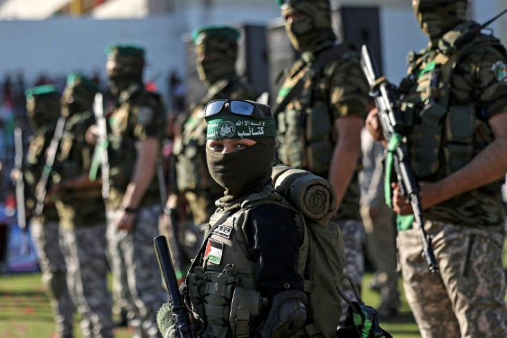 A Palestinian boy carries a toy gun while standing with members of Al-Qassam Brigades, the armed wing of the Hamas movement, during a rally in Gaza City on May 24